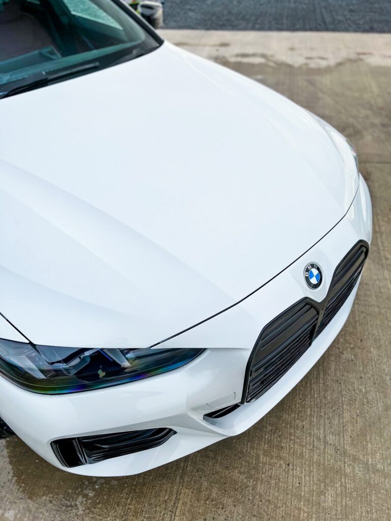 BMW i4 M50 front three-quarter view in white parked outside industrial building in Ireland